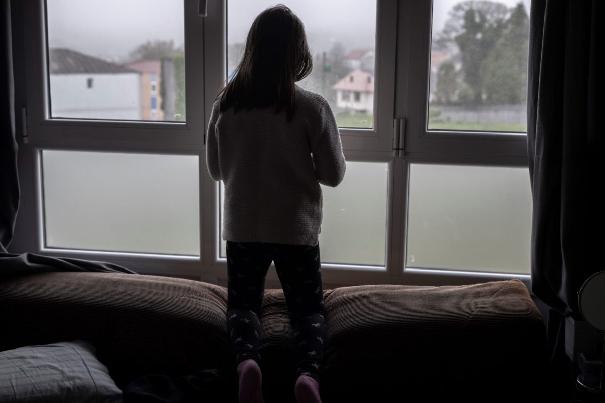 Una niña mira por una ventana. Hoy se celebra el Día de la Depresión
