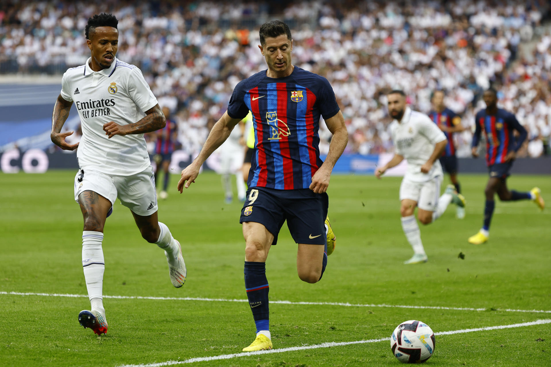 El delantero del FC Barcelona Robert Lewandowski pugna por el balón con el defensa del Real Madrid Éder Militão, durante el partido de Liga que enfrentó a ambos equipos en el Santiago Bernabéu. EFE/ Sergio Pérez