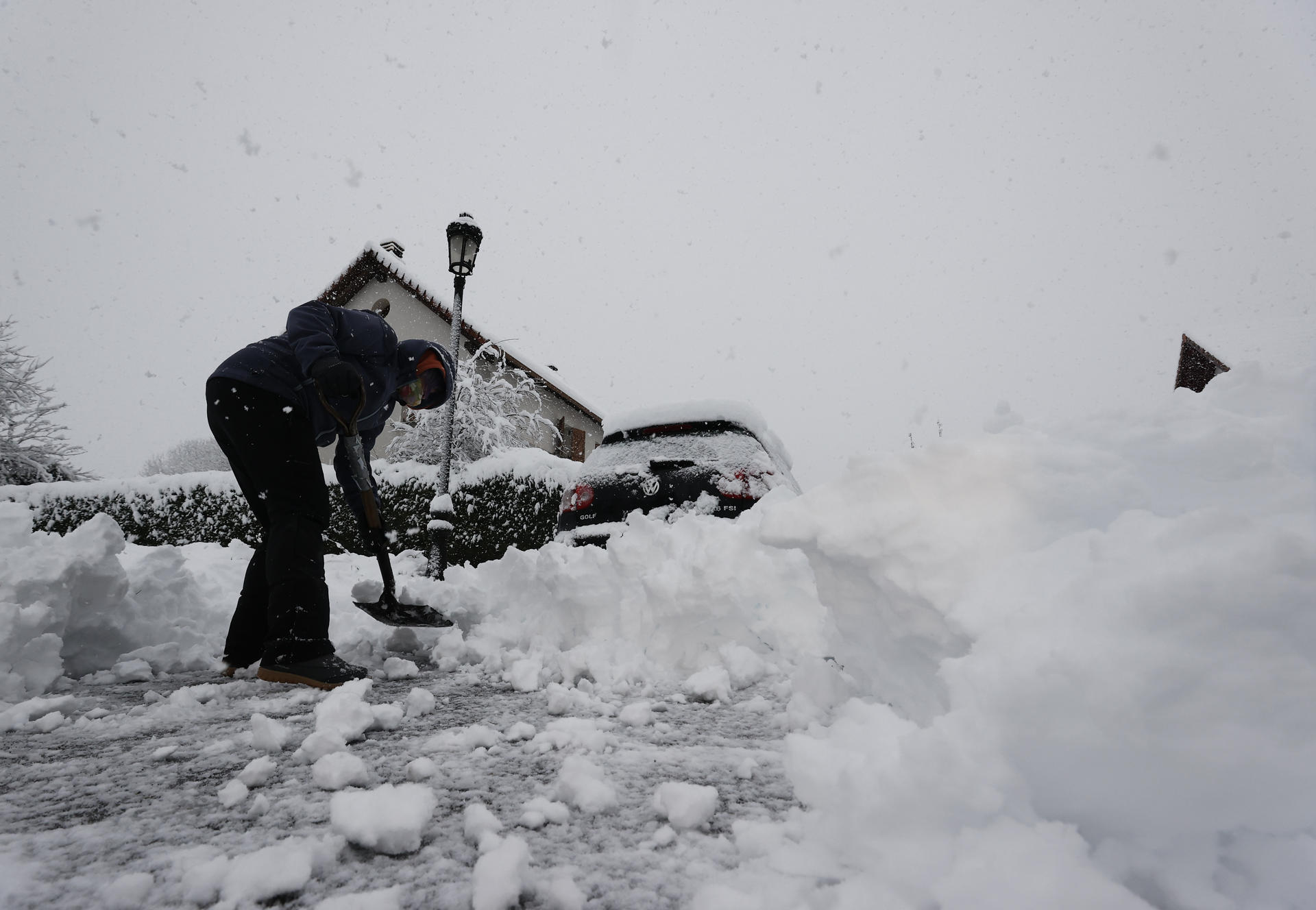 Una persona intenta limpiar de nieve para poder sacar su vehículo de una calle de la localidad de Espinal (Navarra). EFE/ Jesus Diges