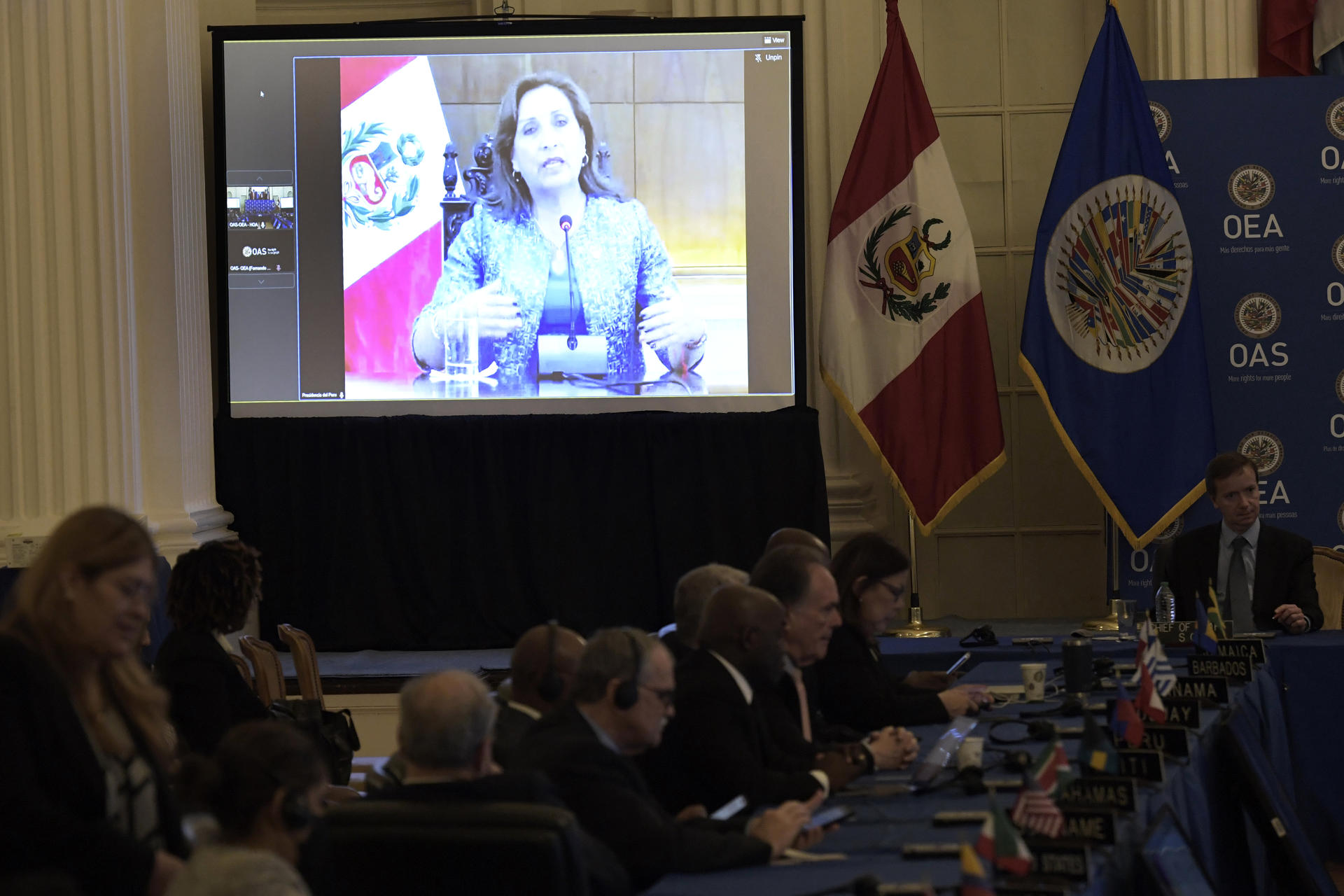 La presidenta peruana, Dina Boluarte (en pantalla), habla durante una intervención virtual ante el Consejo Permanente de la Organización de Estados Americanos (OEA), hoy en la sede del organismo en Washington (EE. UU). Boluarte instó este miércoles a los "países amigos" a que apoyen la propuesta para adelantar la elecciones y lograr una salida "pacífica" a la crisis en la que se haya inmerso Perú. EFE/Lenin Nolly