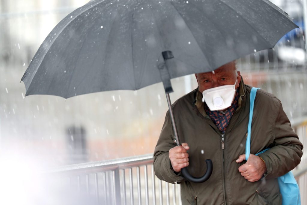 Un hombre protegido con una mascarilla pasea bajo la lluvia. Investigadores han desarrollado una prueba que detecta al mismo tiempo los virus respiratorios más comunes.