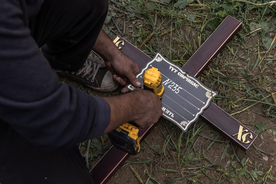Un trabajador coloca una placa con un número en una cruz durante el entierro masivo de personas no identificadas que fueron asesinadas en el distrito de Bucha al noroeste de Kiev, en agosto de 2022.