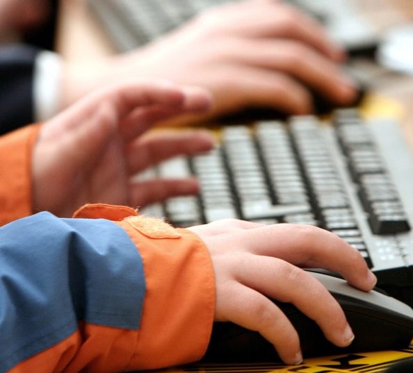 Detalle de la mano de un niño jugando con un ordenador.