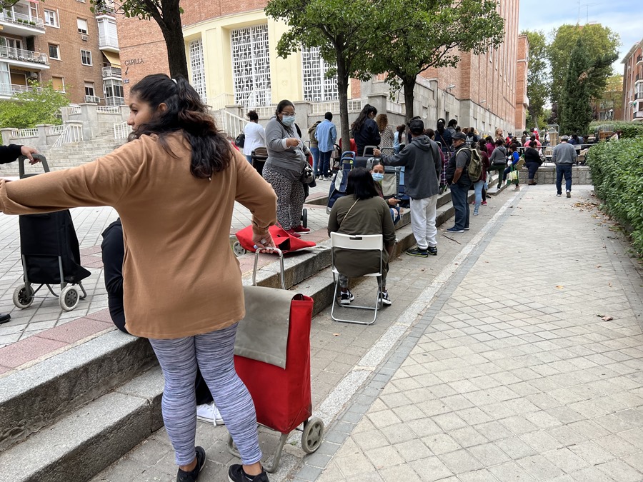 Varias personas esperan para recibir alimentos y otro tipo de asistencia en un centro social en Madrid.