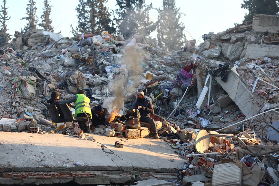 Familiares de personas desaparecidas se calientan alrededor de una hoguera encendida sobre los escombros de un edificio derrumbado por el terremoto en Kahramanmaras, Turquía.