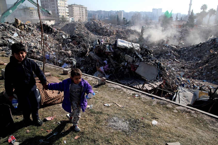 Unos niños juegan junto a un solar de edificios derrumbados tras el terremoto en Kahramanmaras, Turquía.