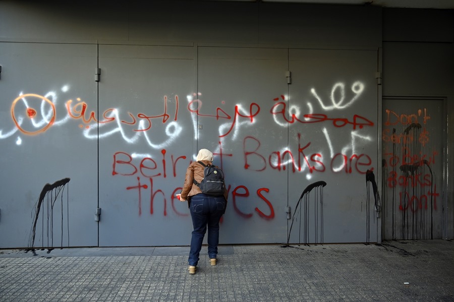 Una persona rocía con pintura la entrada de la sucursal de un banco en Beirut, Líbano.