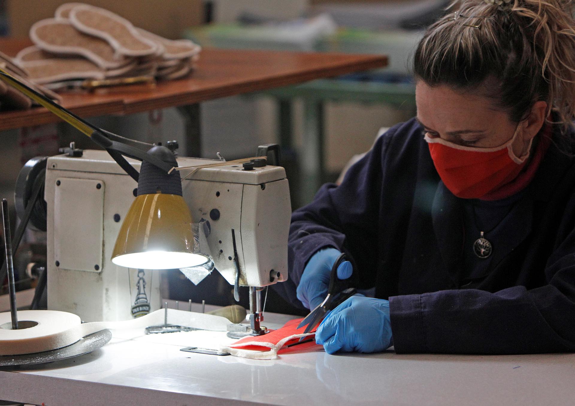 Una trabajadora de una fábrica de calzado de Alicante cose mascarillas durante la pamdemia. EFE/Morell