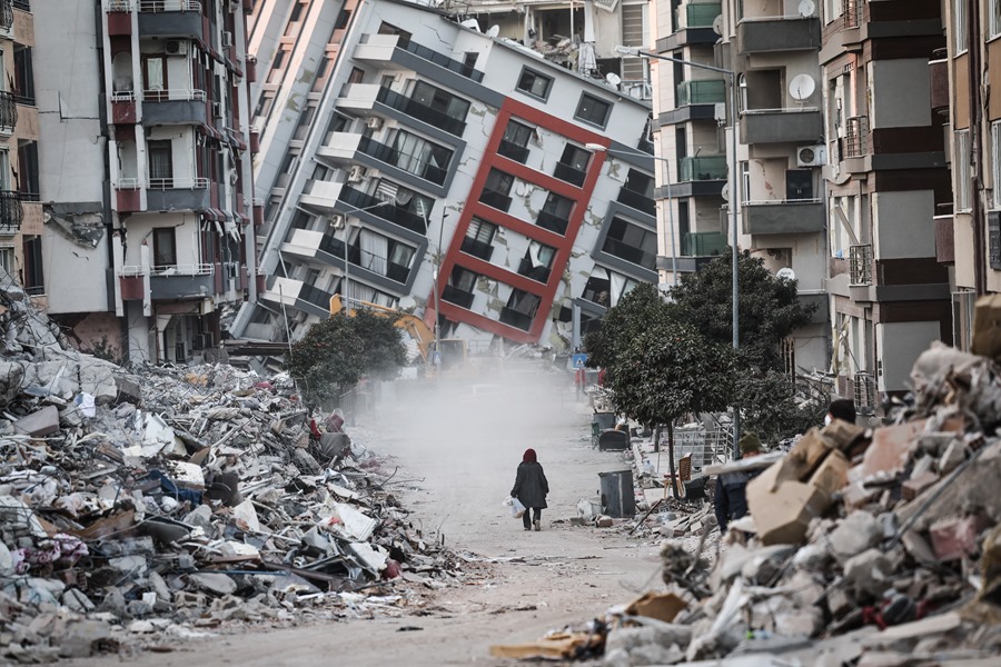 Una mujer pasa junto a edificios en ruinas, tras los terremotos de Turquía