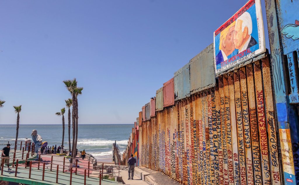 Vista de una pintura del expresidente estadounidense Donald Trump besando al actual mandatario, Joe Biden (d), el 28 de marzo de 2023 en el muro fronterizo en la ciudad de Tijuana en Baja California (México). EFE/Joebeth Terriquez