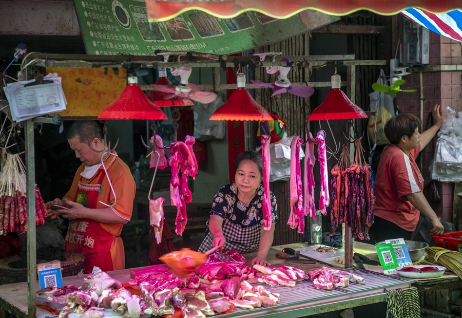 Una mujer ahuyenta a las moscas en un puesto del mercado de carne de Guangzhou, China.