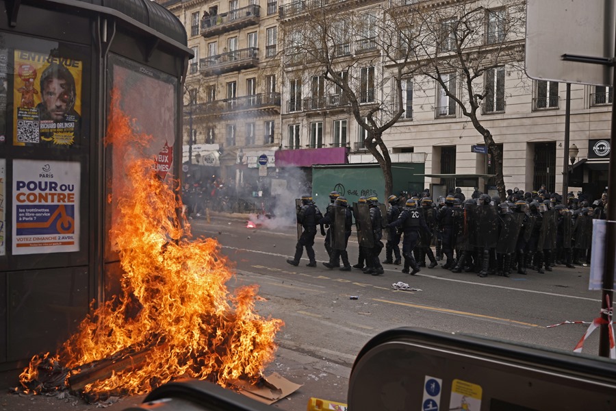 Un quiosco es incendiado mientras policías franceses se enfrentan a manifestantes durante una de las protestas convocadas esta semana contra la reforma gubernamental del sistema de pensiones en París.