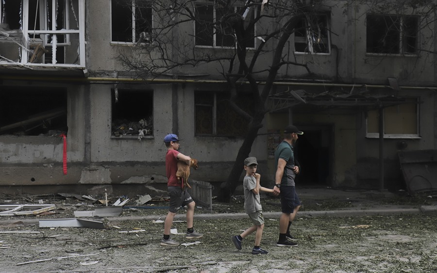 Varias personas caminan por una calle, en medio de edificios destruidos en Bajmut, Ucrania.