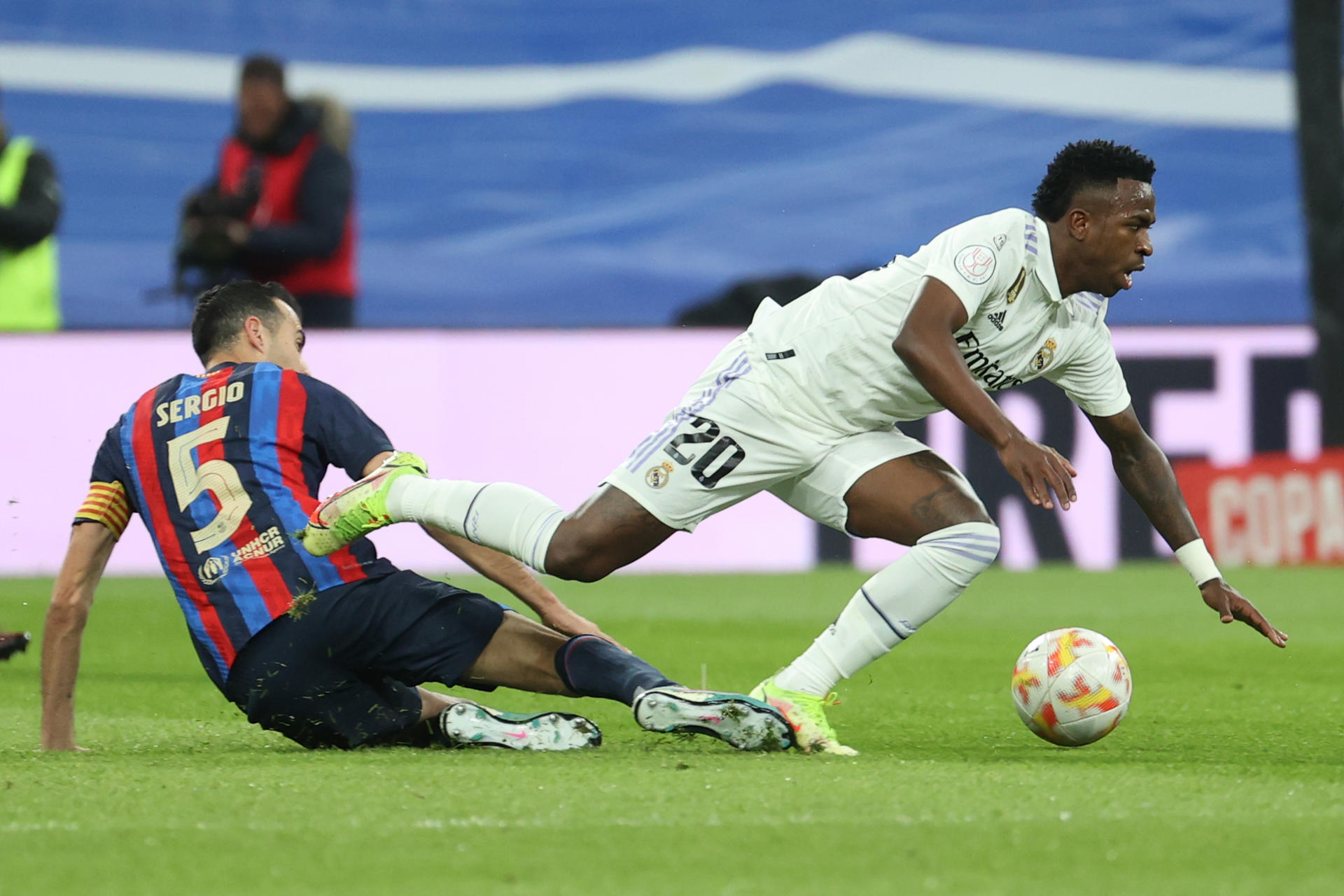 Real Madrid's Vinicius Jr. (R) tries to get past Sergio Busquets of FC Barcelona during the Copa del Rey semifinal first leg at the Santiago Bernabeu in Madrid on 2 March 2023. EFE/Juanjo Martin
