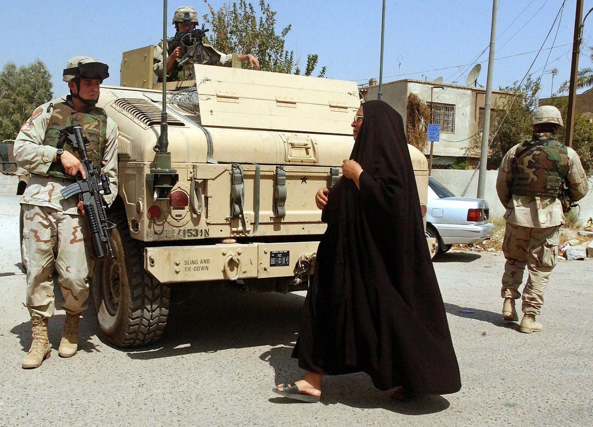 Fotografía de archivo fechada el 8 de septiembre de 2004 que muestra a una mujer iraquí que se cruza con soldados estadounidenses que patrullan las calles de Bagdad (Irak). EFE/Mohammed Messara