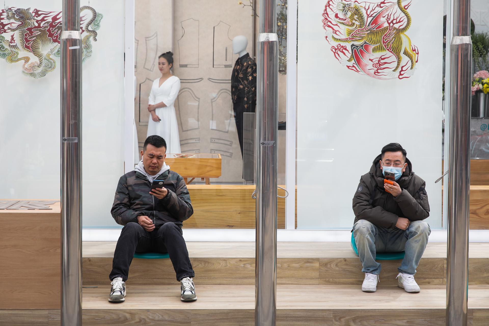 People use their cellphone on the street in Beijing, China, 24 March, 2023. EFE/EPA/WU HAO