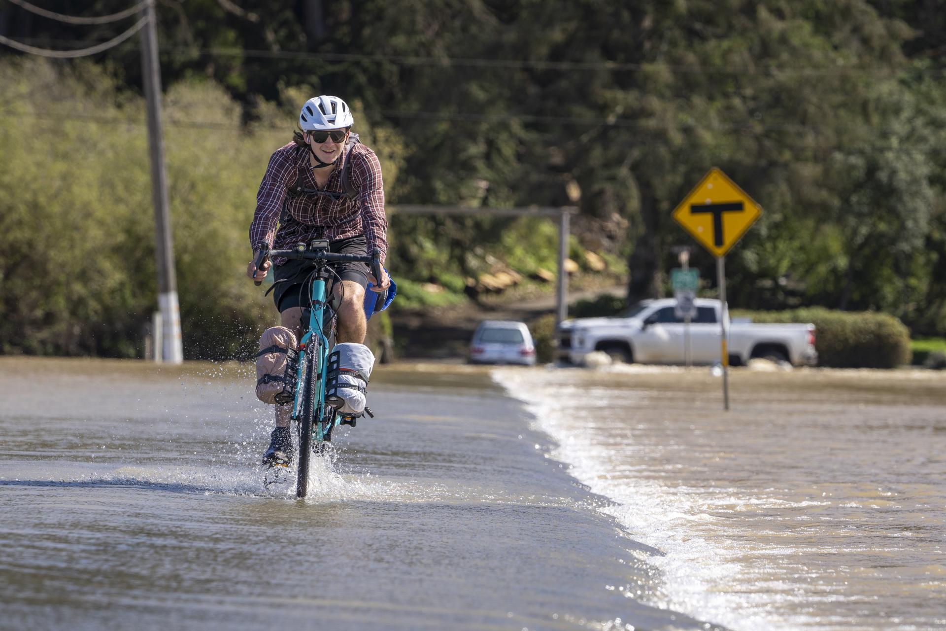 David MacKay, from Newfoundland Canada, bikes on a flooded road in an agricultural area flooded from a breached levee on the Pajaro River in Monterey County after storms hit Northern California in Pajaro, California, USA, 15 March 2023. EFE/EPA/LIPO CHING