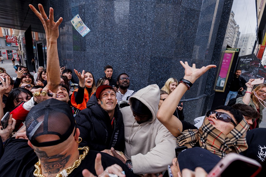 El rapero Yung Beef (c), rodeado de guardaespaldas, lanza billetes reales para promocionar su último trabajo, este jueves en el centro de Madrid. 