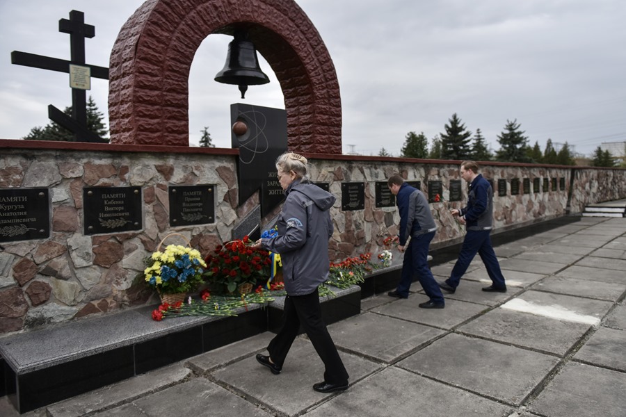 Varios trabajadores depositan flores en un memorial de la central eléctrica de Chernobyl con motivo del 37 aniversario del desastre nuclear de la planta ucraniana.