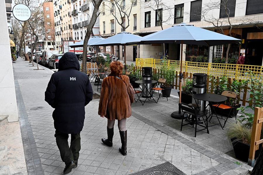 Varias personas pasan junto a la terraza de un bar instalada en la calle Alonso Cano de Madrid.