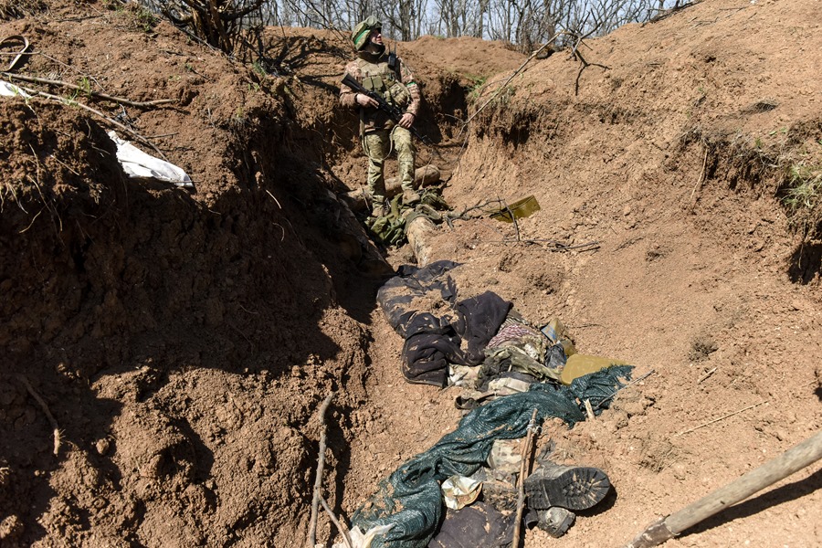 Un militar ucraniano pasa junto a presuntos cuerpos rusos en una trinchera ubicada en un territorio reconquistado no revelado cerca de Bajhmut, en la región ucraniana de Donetsk.