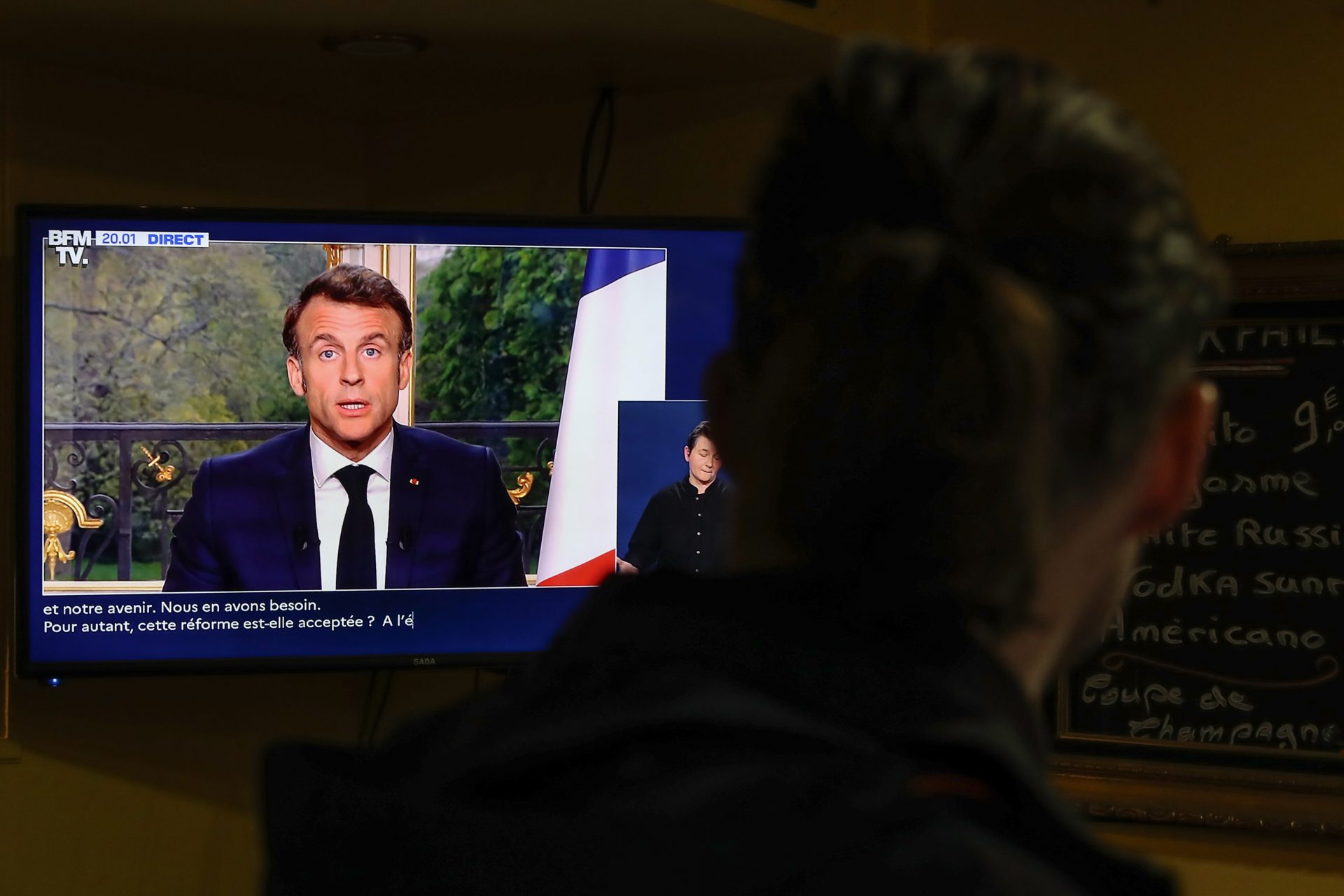 Un hombre ve la televisión en la que aparece el presidente francés, Emmanuel Macron.
