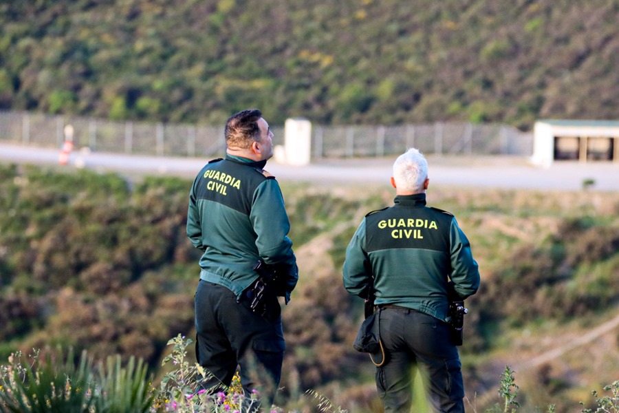 Dos agentes de la Guardia Civil vigilan desde un monte junto a la zona fronteriza en Ceuta con Marruecos. 