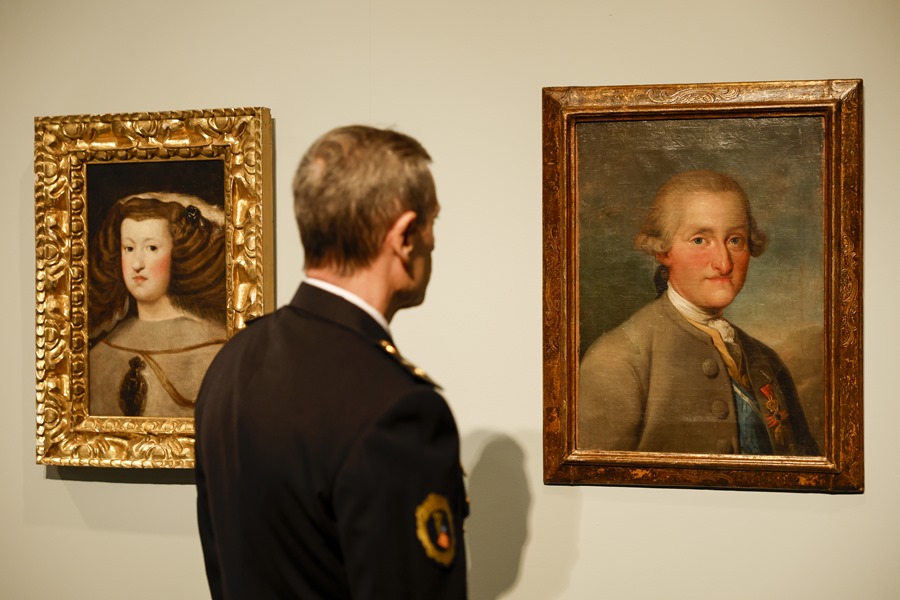 Un agente de la Unidad de Patrimonio de la Policía de la Generalitat contempla las pinturas falsificados de Velázquez "Mariana de Austria" (i) y de Goya "Carlos IV".