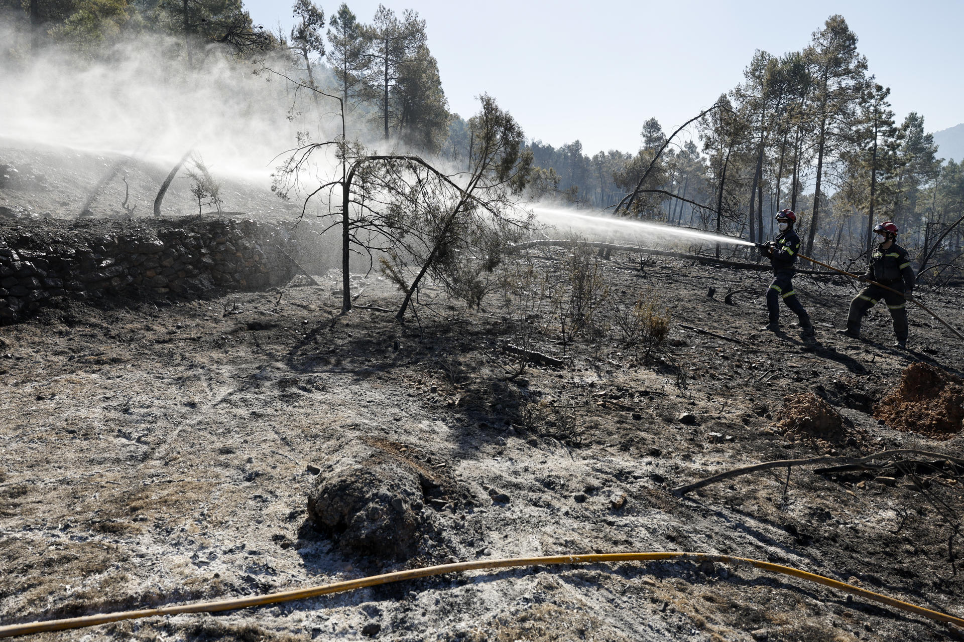 En la imagen, bomberos refrescan los alrededores de Montán, durante el incendio de Villanueva de Viver. EFE/ Biel Aliño