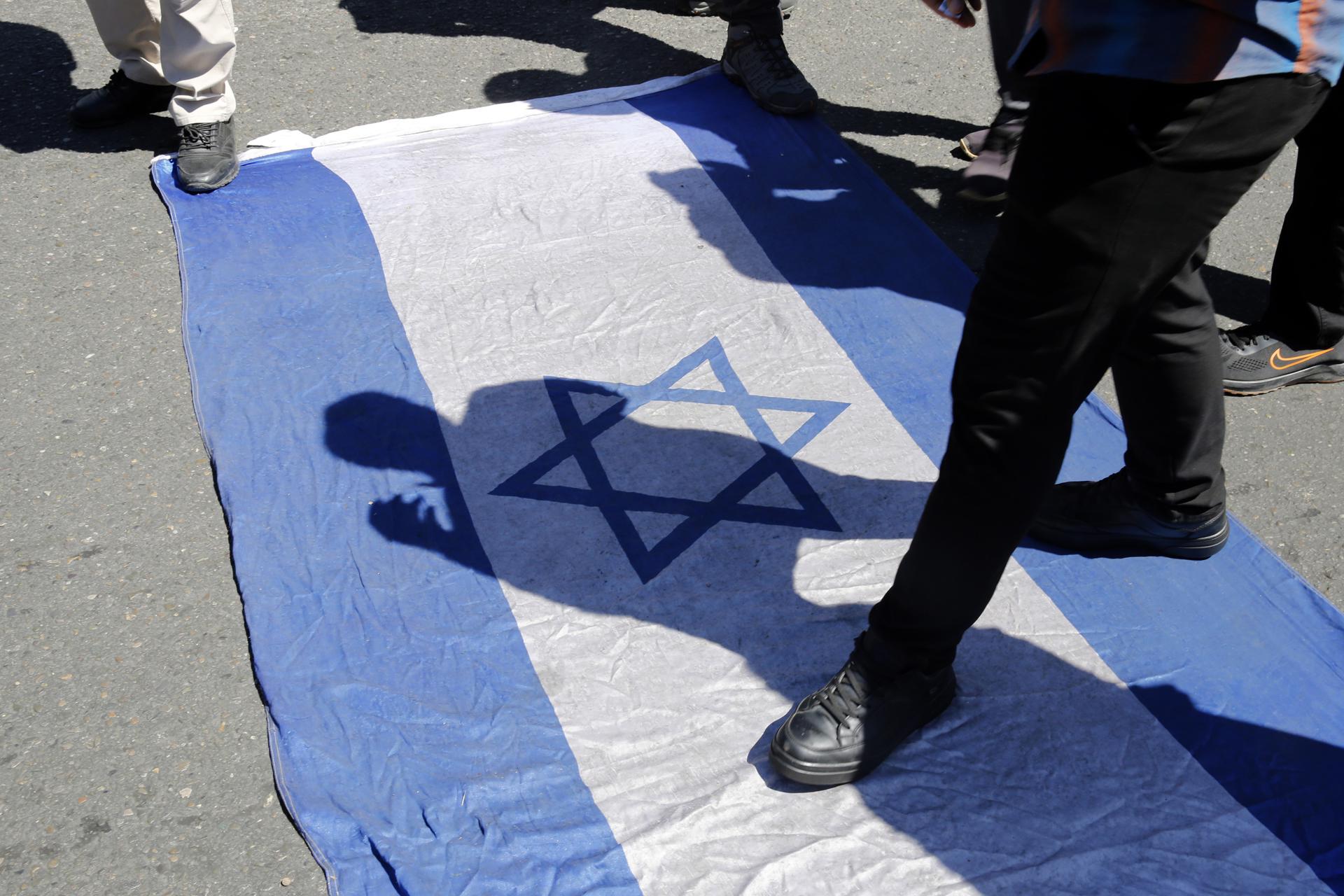 Iranians walk over an Israeli flag during a rally marking Al Quds Day in Tehran, Iran, 14 April 2023. EFE/EPA/ABEDIN TAHERKENAREH