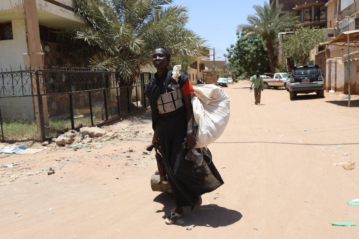 Una mujer camina con sus pertenencias por una calle de Jartum.