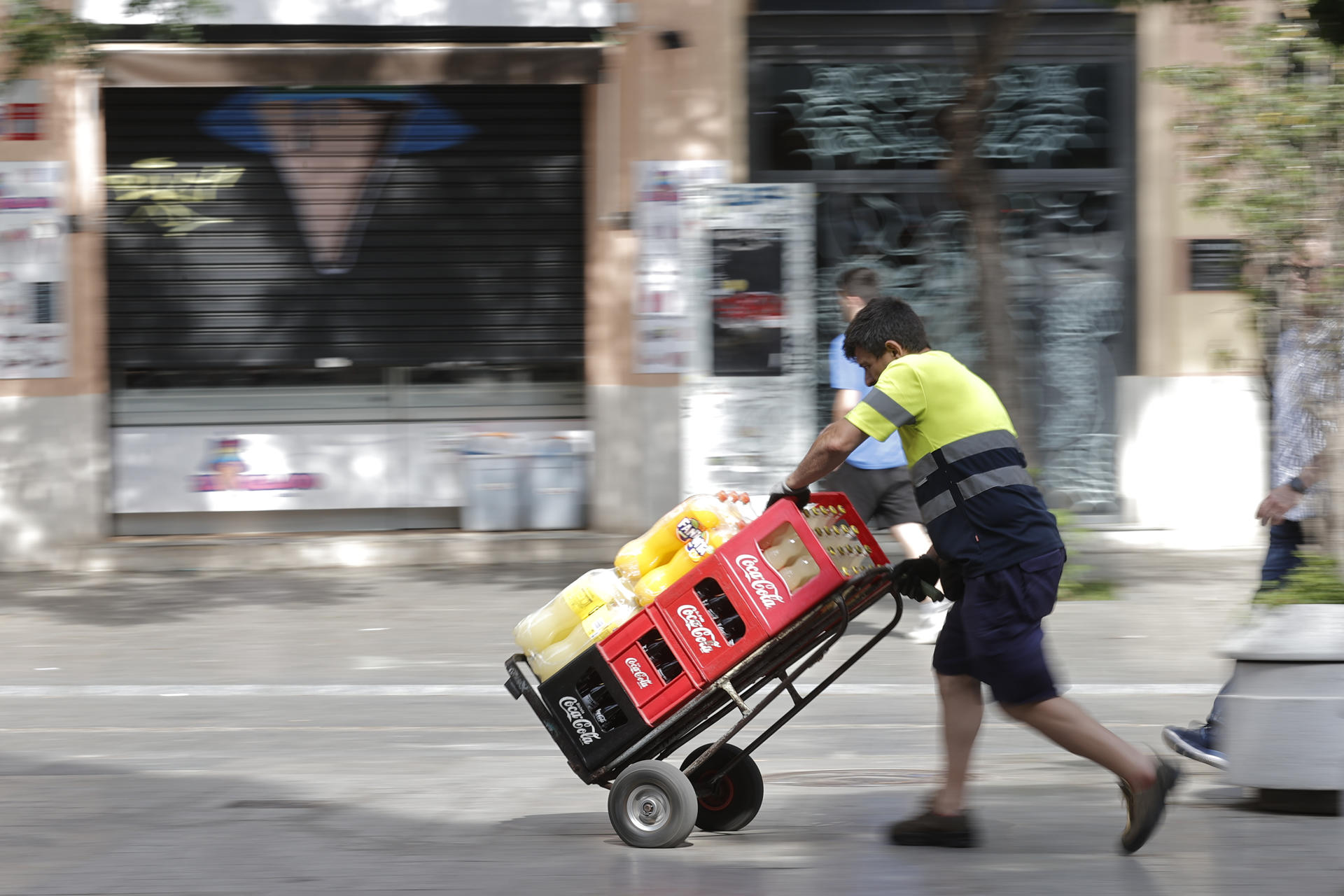 Un trabajador transporta una carretilla con bebida. EFE/Manuel Bruque/Archivo
