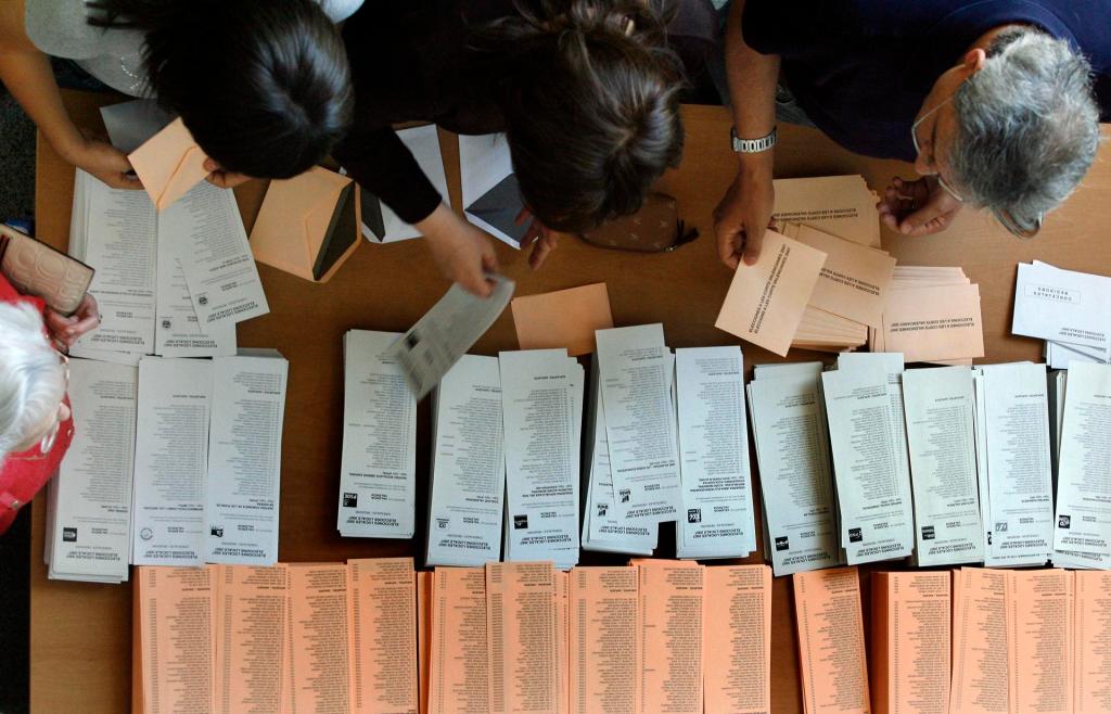 Varias personas eligen las papeletas para elegir alcaldes y diputados autonómicos en un colegio electoral de la Comunitat Valenciana. EFE/Kai Försterling/Archivo
