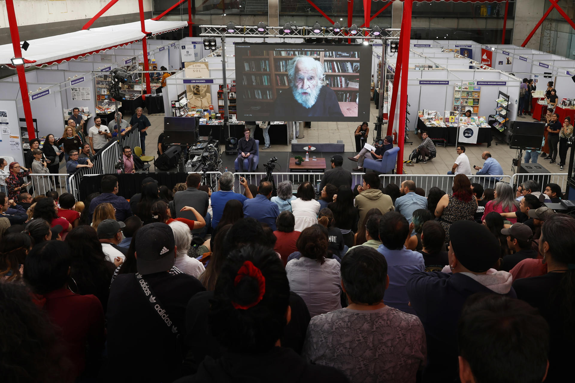 Decenas de personas escuchan la intervención por vía telemática de Noam Chomsky, este 12 de abril de 2023, durante la Feria del Libro de Recoleta, en Santiago (Chile). EFE/ Elvis González