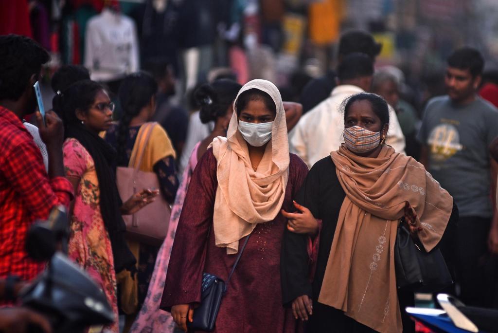 Dos mujeres caminan entre la multitud por una calle de Chennai, India.