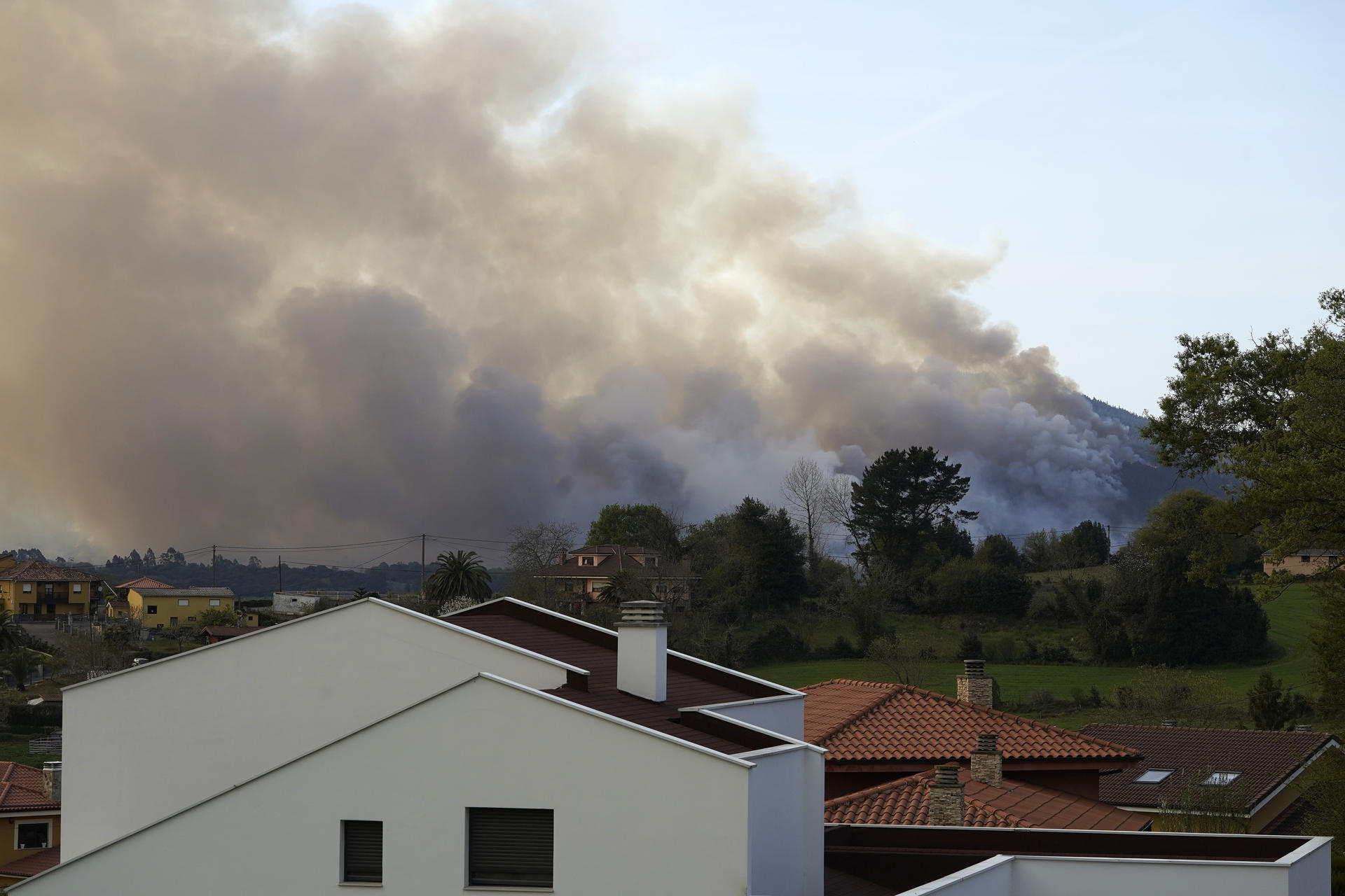 Una hilera de casas, muy próximas a un incendio en los montes de Soto de las Regueras, Asturias. EFE/Paco Paredes