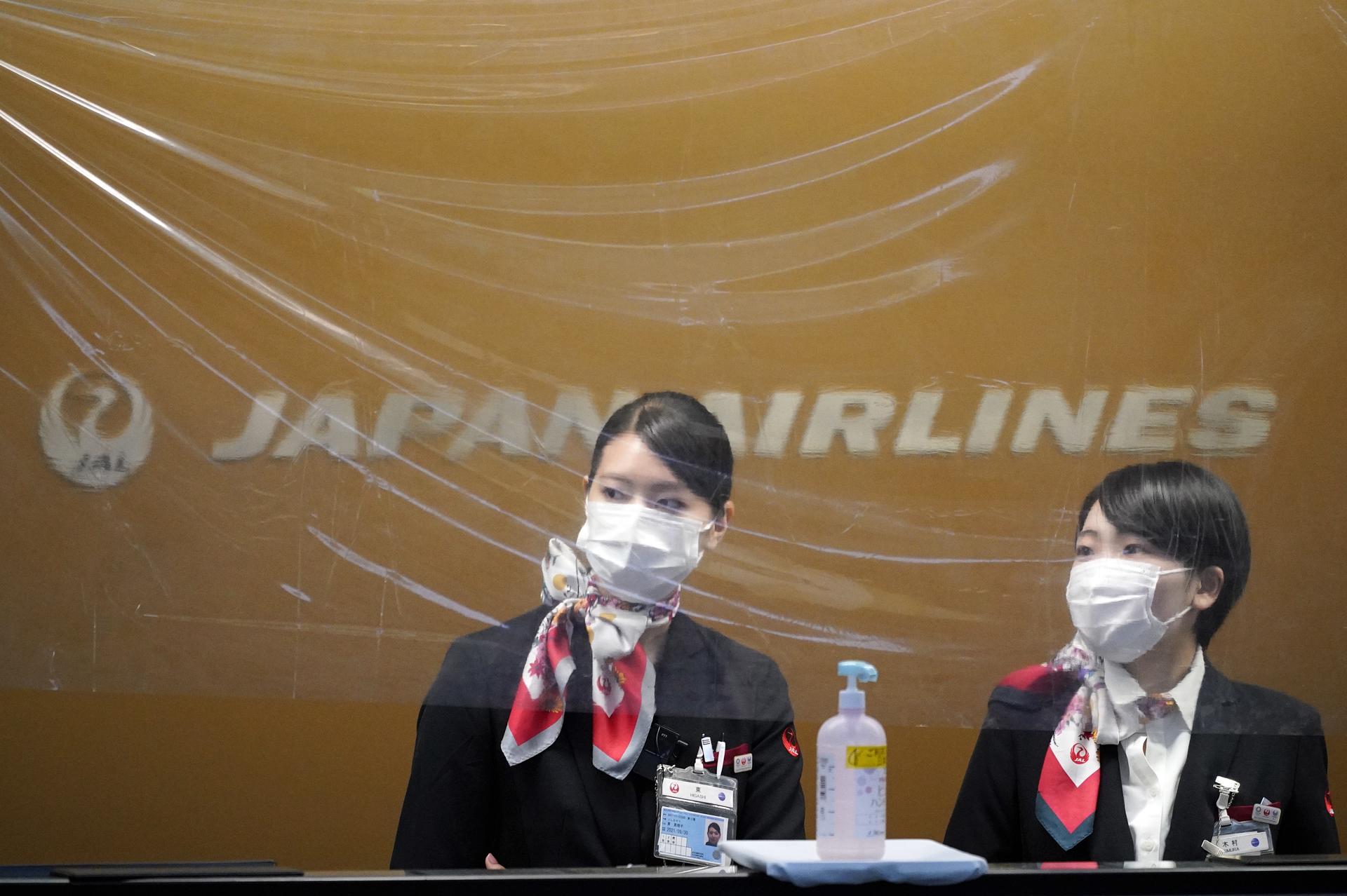 Japan Airlines (JAL) ground staff members wear protective gear and stand behind a plastic sheet for protection against COVID-19 disease infection at Haneda Airport in Tokyo, Japan, 28 April 2020 (issued 30 April 2020). EFE-EPA FILE/FRANCK ROBICHON
