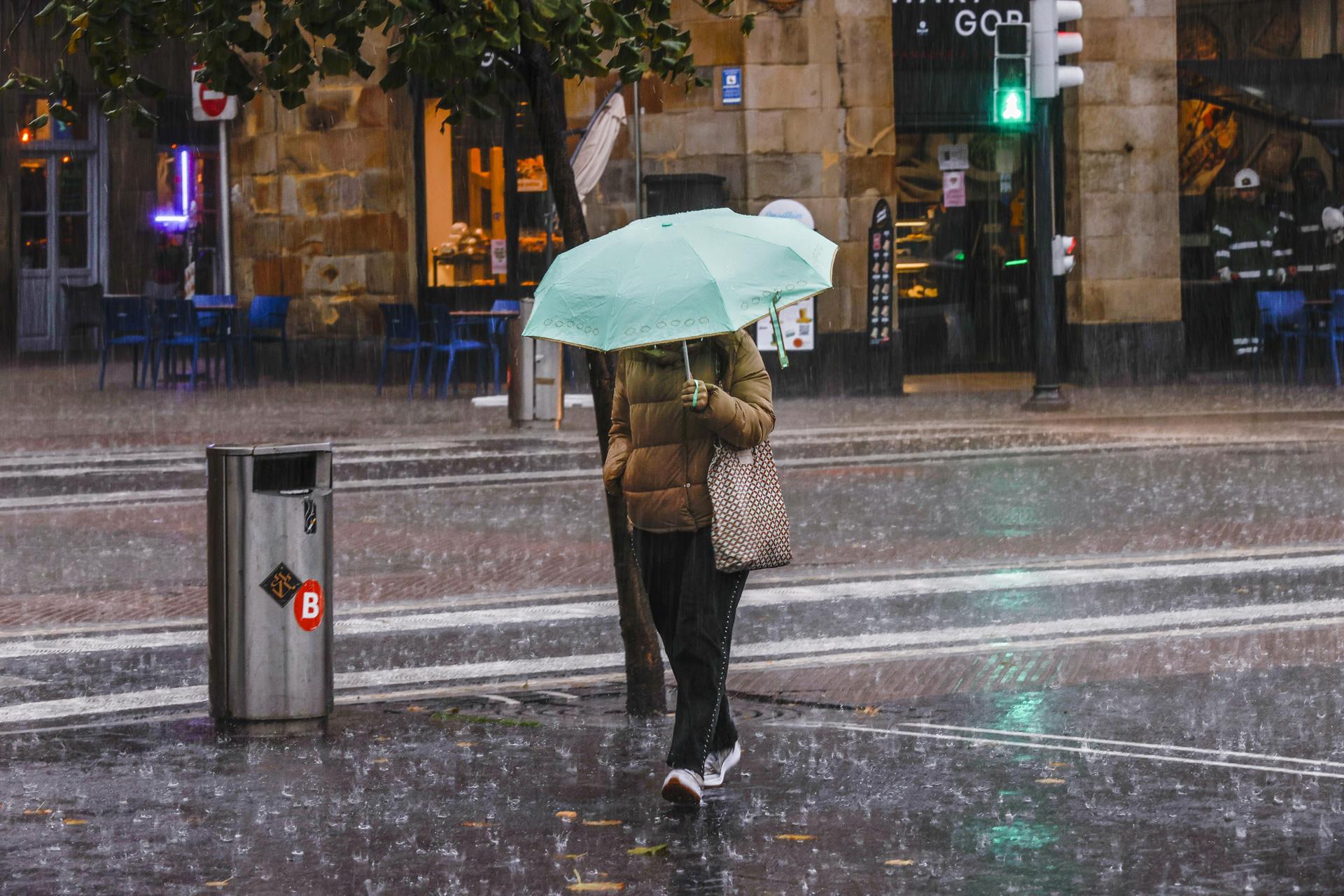 En la imagen de archivo, una mujer camina bajo un fuerte aguacero en Bilbao. EFE/Miguel Toña