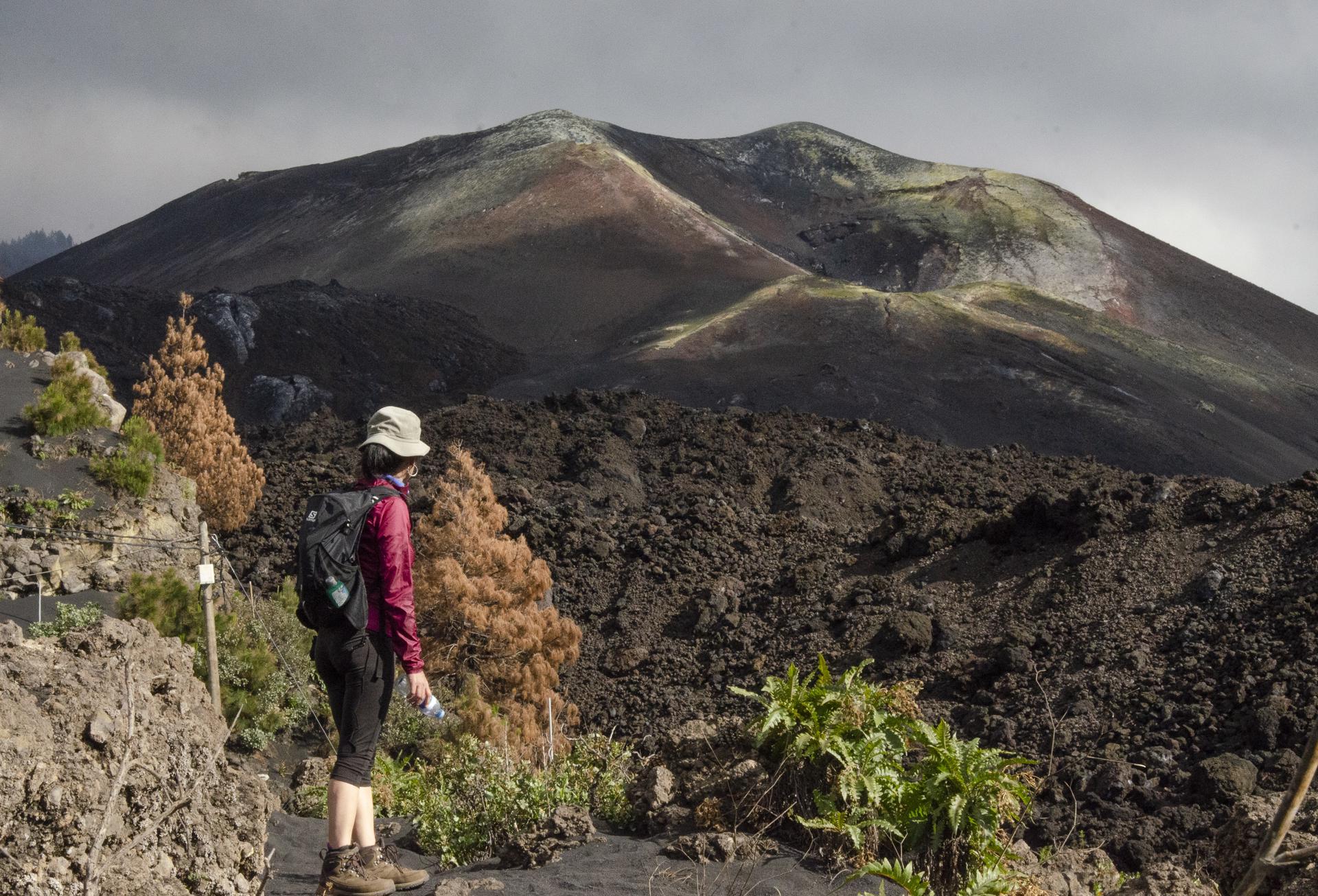 Foto de archivo de una turista realizando una ruta de senderismo junto a una colada de la erupción de La Palma. EFE/Miguel Calero