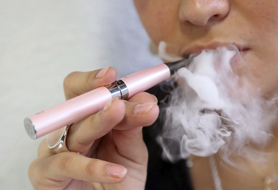 Una mujer fuma un cigarrillo electrónico que, junto con los vapeadores, han favorecido a la reducción de edad del primer contacto con la nicotina a los 11 años.