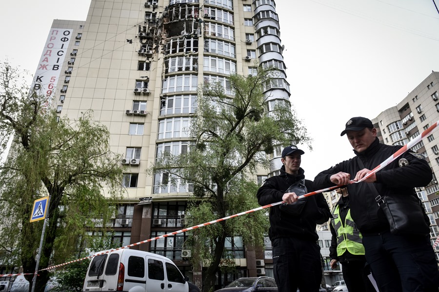 Oficiales de policía colocan cinta adhesiva en el acceso a un bloque de apartamentos dañado por el ataque de un dron ruso en Kiev, esta madrugada