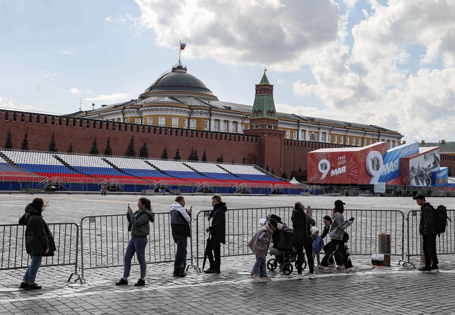 Varias personas contemplan el Kremlin mientras la bandera del presidente de Rusia ondea sobre su residencia en la Plaza Roja en Moscú.
