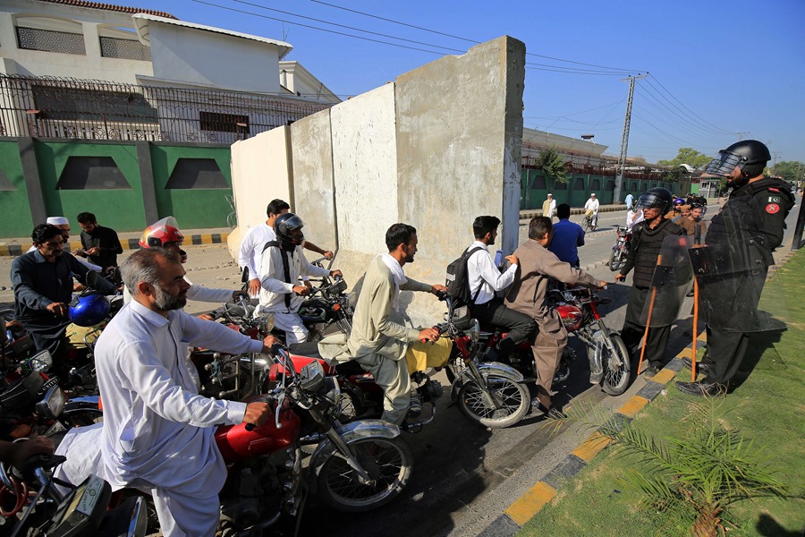 Funcionarios de seguridad paquistaníes revisan el tráfico en un control de carretera un día después de las protestas por el arresto de Imran Khan, exprimer ministro y jefe del partido de oposición Pakistán Tehreek-i-Insaf (PTI), en Peshawar, Pakistán. 