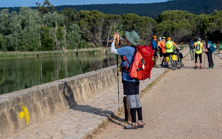 Una peregrina del Camino de Santiago se detiene para hacer una fotografía a su paso por el pantano de la Grajera, en Logroño. 
