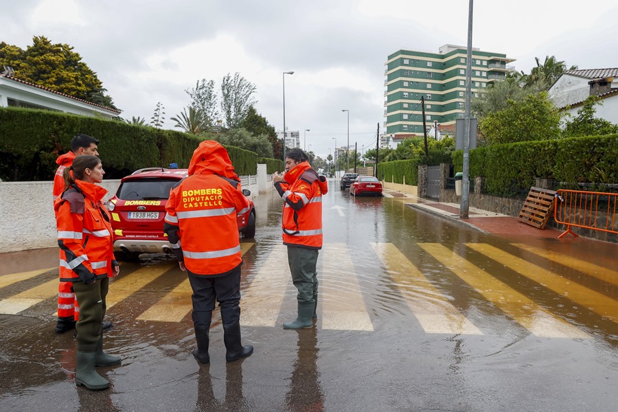 Varios bomberos aguardan en una calle inundada cuando el episodio de lluvias torrenciales ha dejado un registro histórico en Benicàssim.