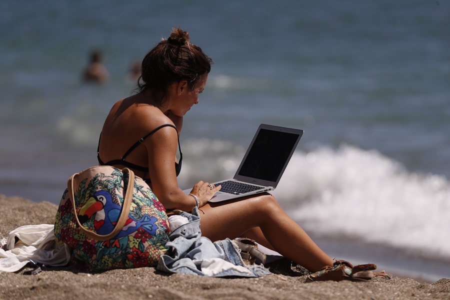Una mujer toma el sol mientras mira su ordenador portátil. Hoy se celebra el Día Mundial de la Contraseña