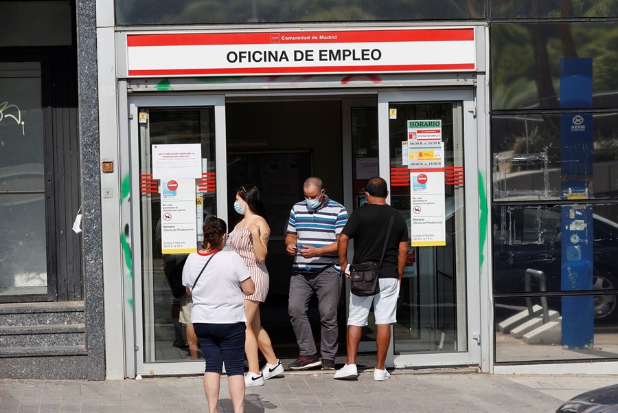 Several people leave and enter an employment office in Madrid.  Economists forecast growth in Spain