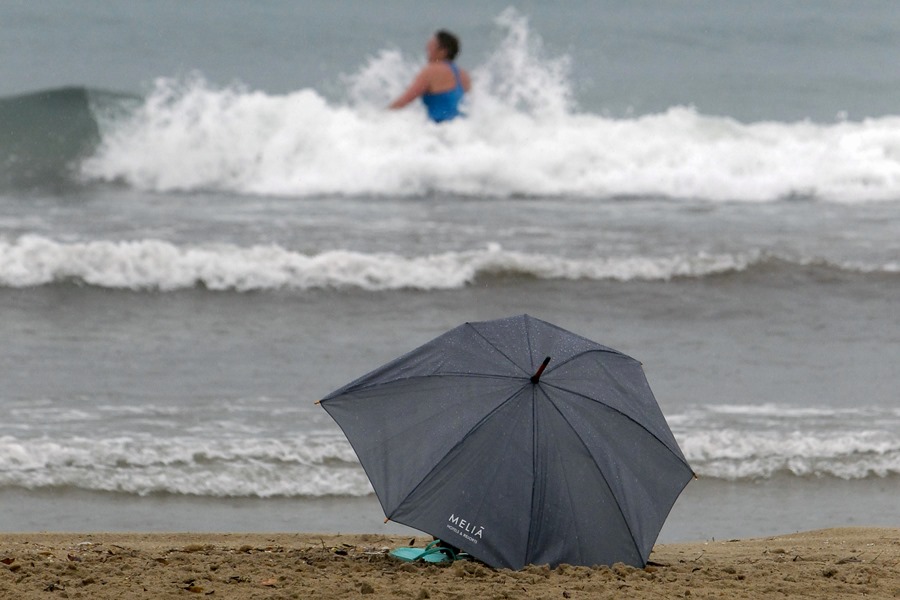 Una persona se baña bajo la lluvia en las aguas de la playa de El Postiguet de Alicante.
