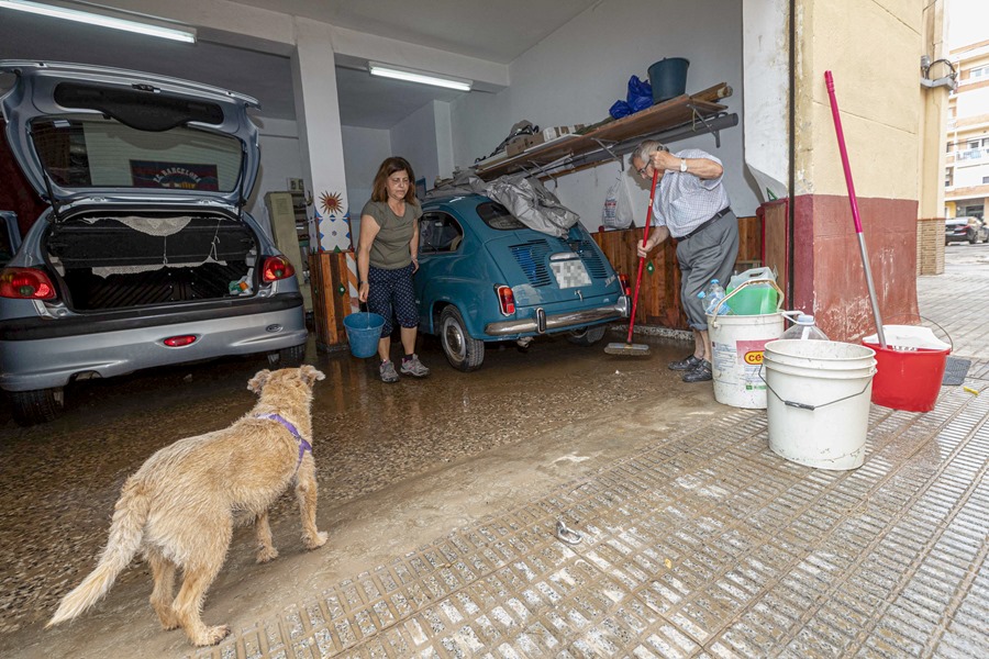 Dos vecinos del barrio de San Ginés de Cartagena limpian el garaje de su vivienda, tras las fuertes lluvias.