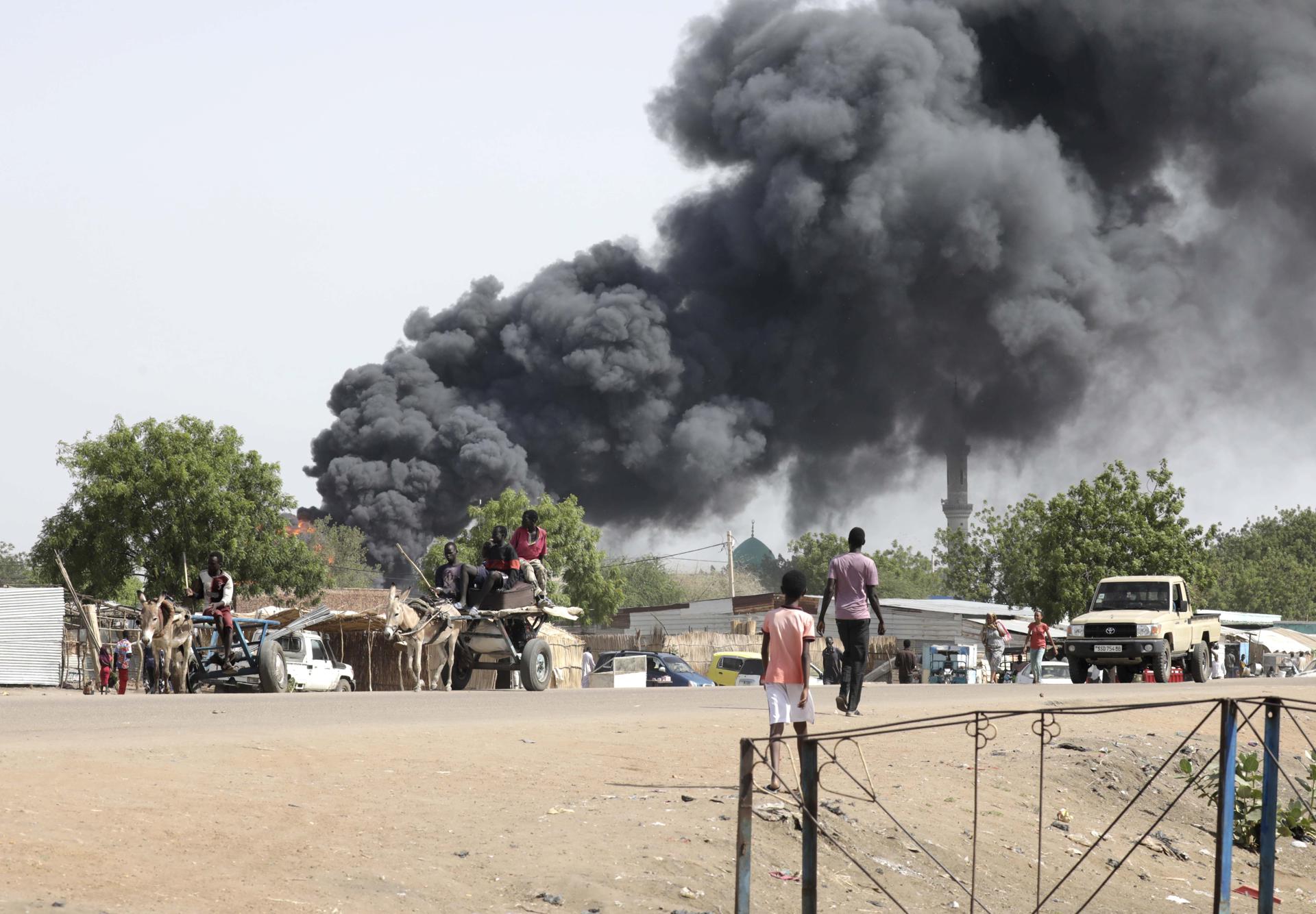 People drive as smoke rises from a fire at a market in the Upper Nile State town of Renk, South Sudan, 13 May 2023. EFE-EPA/AMEL PAIN